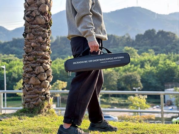 Man in het park die de JNC MC599 dipool antenne in de meegeleverde opbergtas meeneemt