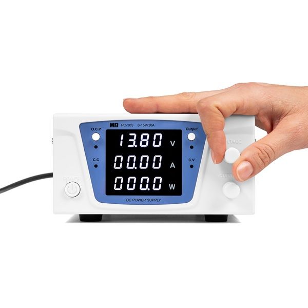 Een hand die een draaiknop op de MFJ-PC-30 digitale 30 ampère voeding bediend