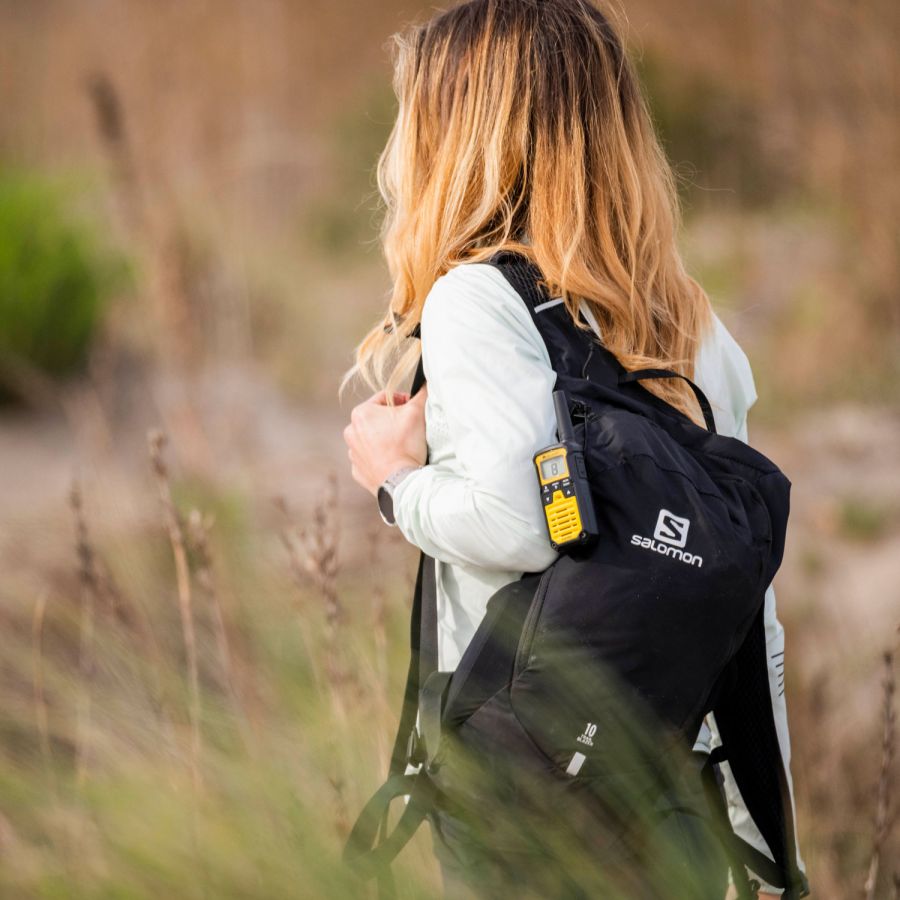 Midland XT50 Pro PMR446 portofoon bevestigd aan een rugzak van een vrouw tijdens outdoor activiteit