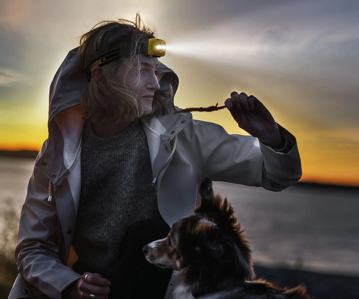 Vrouw samen met haar hond in de schemering met een GP CH42 hoofdlamp in gebruik