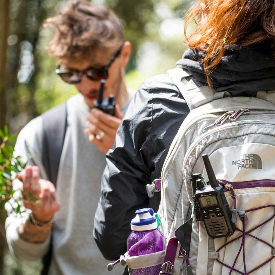 Midland XT-70 Pro portofoon aan een rugzak en een exemplaar die wordt gebruikt door een jongen