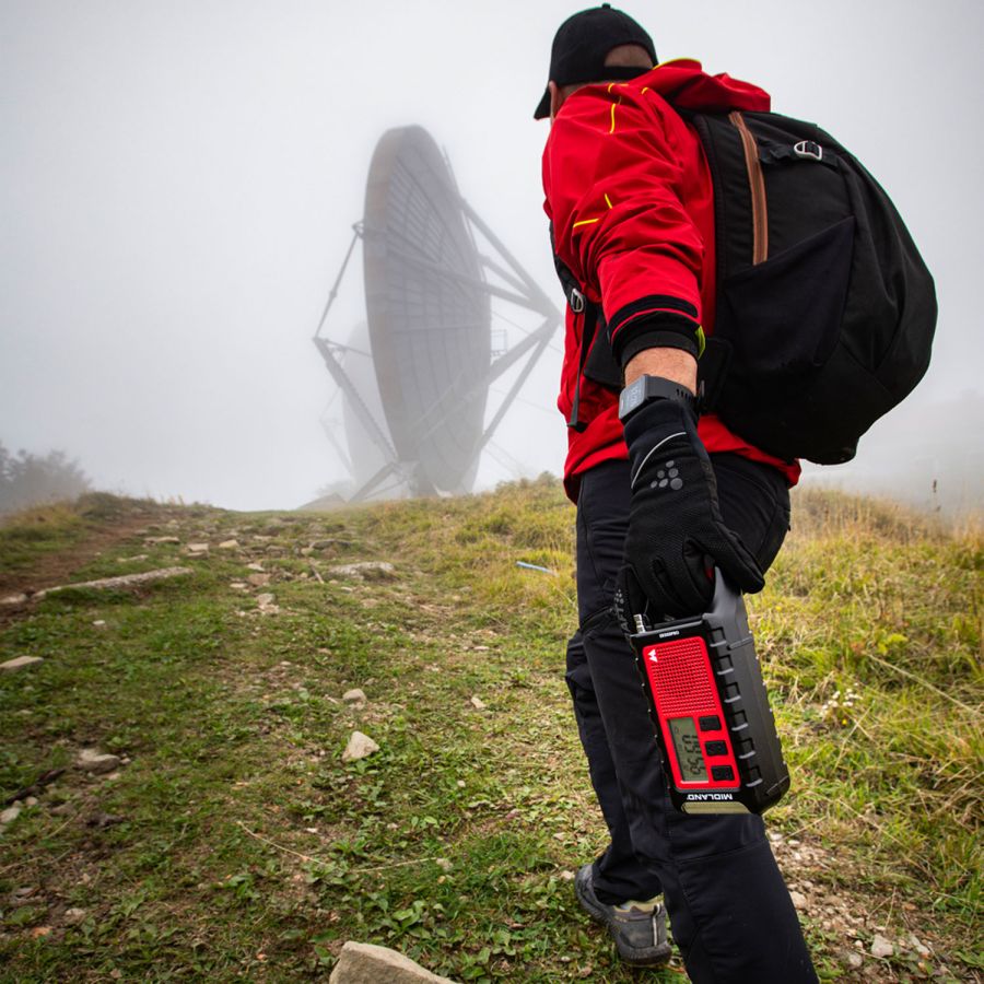 man met midland er300 pro noodradio met bluetooth powerbank, zaklamp en draaislinger om zelf op te laden