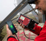 Man die zijn mobiele telefoon oplaad met behulp van de Midland ER300 noodradio met zonnepaneel, handdynamo en geïntergreerde zaklamp